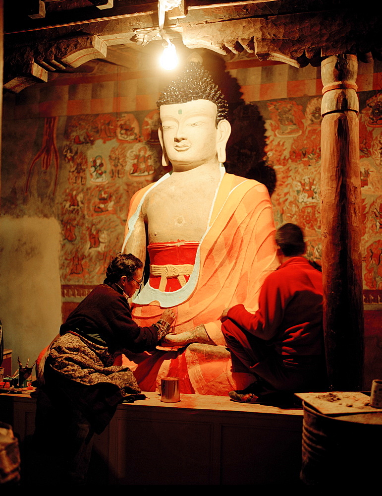 Restorers painting buddha statue in prayers room of convent Tiksey Gonpa, southeast of Leh, Ladakh, Jammu and Kashmir, India