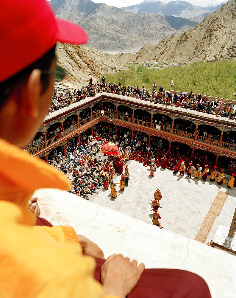 Young monk on the roof looking at the dance of masks in the courtyard during the Hemis Gonpa Festival at convent Hemis, southeast of Leh, Ladakh, Jammu and Kashmir, India