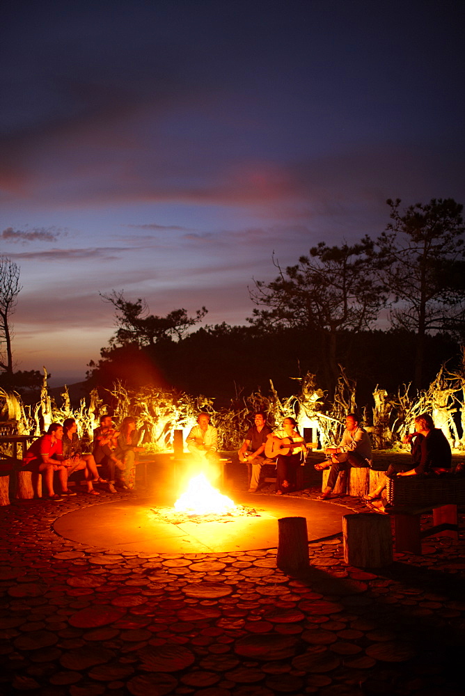 Guests sitting around the camp fire called 'Ring of Fire' in the garden of Hotel Areias do Seixo, Povoa de Penafirme, A-dos-Cunhados, Costa de Prata, Portugal