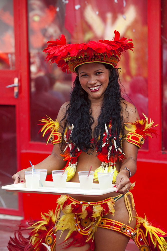 Cheerful woman serving drinks at Miscigenacao dance and folklore show with Boi Bumba festival costumes, Parintins, Amazonas, Brazil