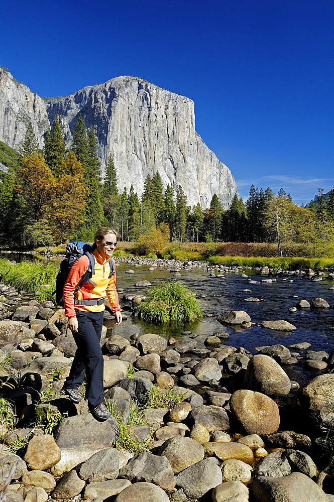 Woman wearing rucksack hiking on stony brookside, Yosemite National Park, California, North America, America