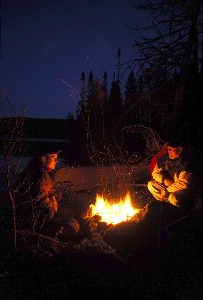 Men sit Beside Campfire