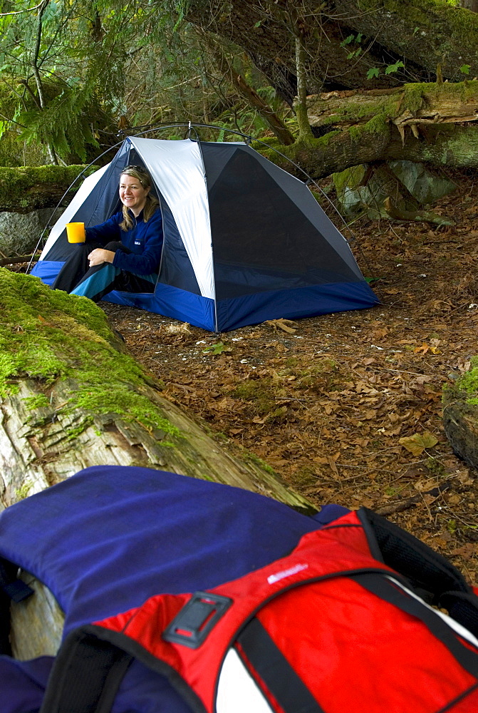 Woman enjoying morning coffee, camping at beach below Friel Falls, Hotham Sound, British Columbia