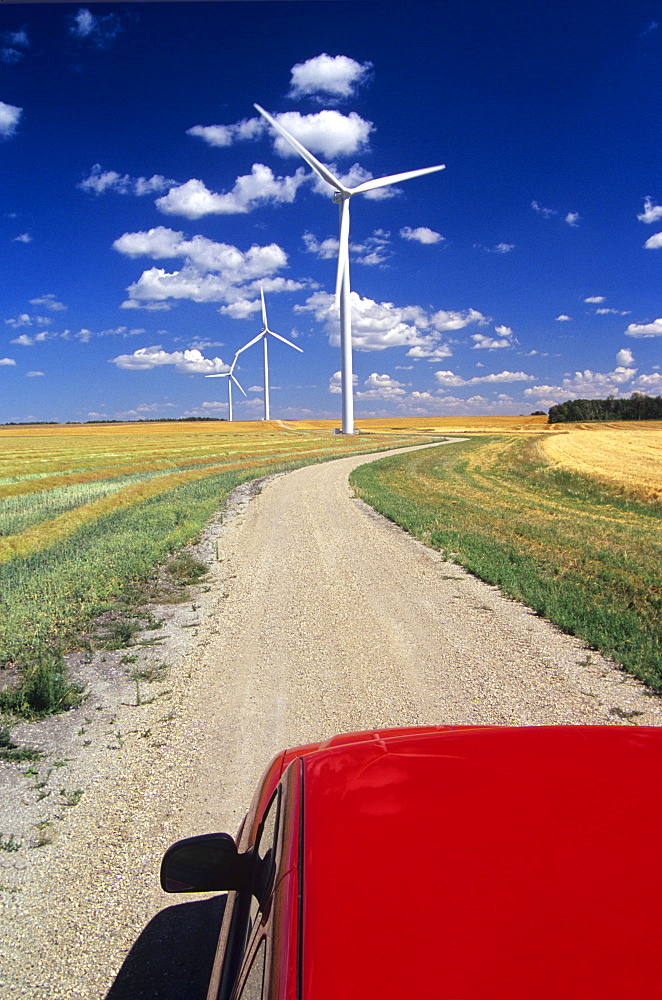 View of a Truck and Wind Turbines on Road through Cropland, near St. Leon, Manitoba