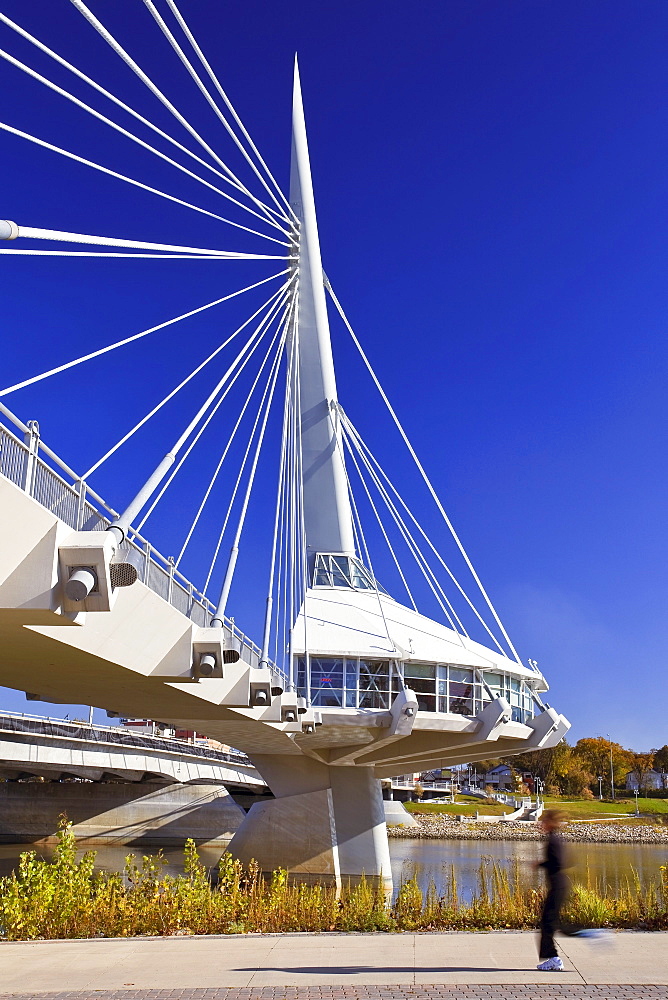 Woman jogging along Red River, in front of Esplanade Riel Pedestrian Bridge, Winnipeg, Manitoba