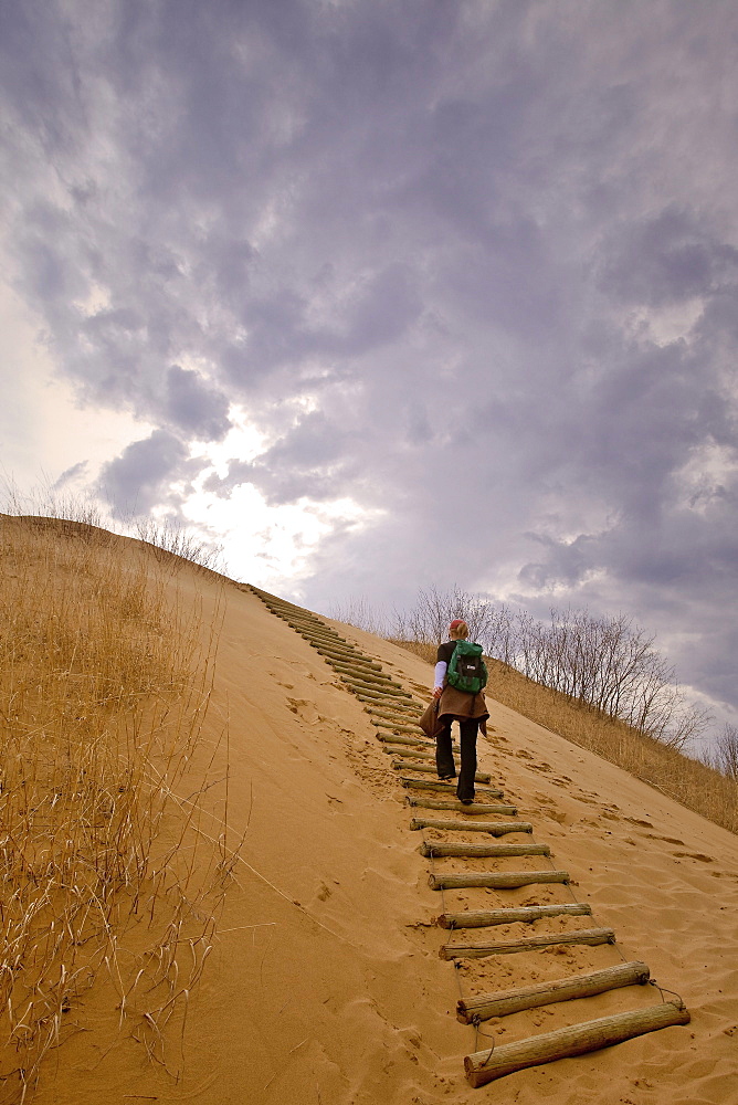 Woman hiking up a sand dune, The Spirit Sands, Spruce Woods Provincial Park, Manitoba
