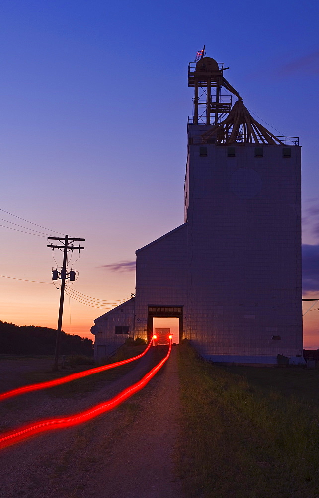 Streak of truck lights and an old grain elevator, Virden, Manitoba