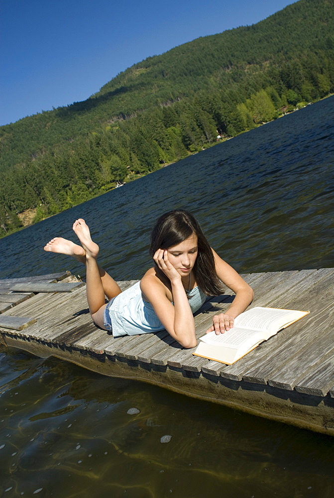 Teenager reading on a dock, Shawnigan Lake, Victoria, British Columbia