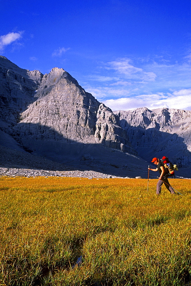 Hiker on grass beneath walls of Mount MacDonald, Mayo, Yukon