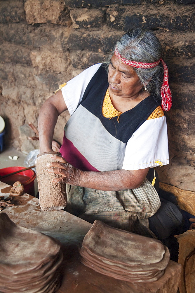 Old Purupecha woman making pottery candle stick holders, Santa Fu de la Laguna, Michoacun, Mexico