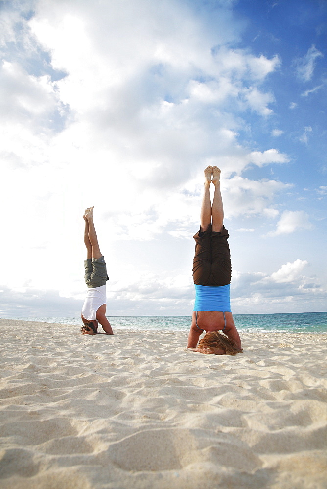 Hawaii, Oahu, Lanikai, Young couple doing yoga, stay in a headstand position on the beach.