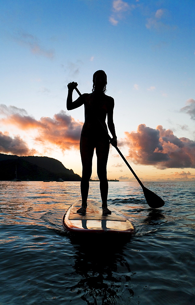 Hawaii, Kauai, Woman stand up paddling in ocean, Beautiful sunset.