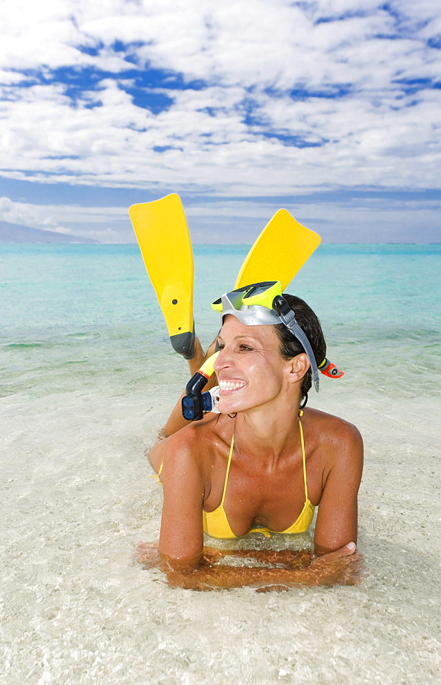 Woman wearing snorkel gear near ocean's edge.