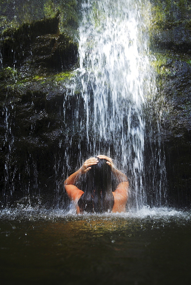 Hawaii, Oahu, Manoa Falls, Beautiful female sitting in a pond at the bottom of Manoa Waterfalls.