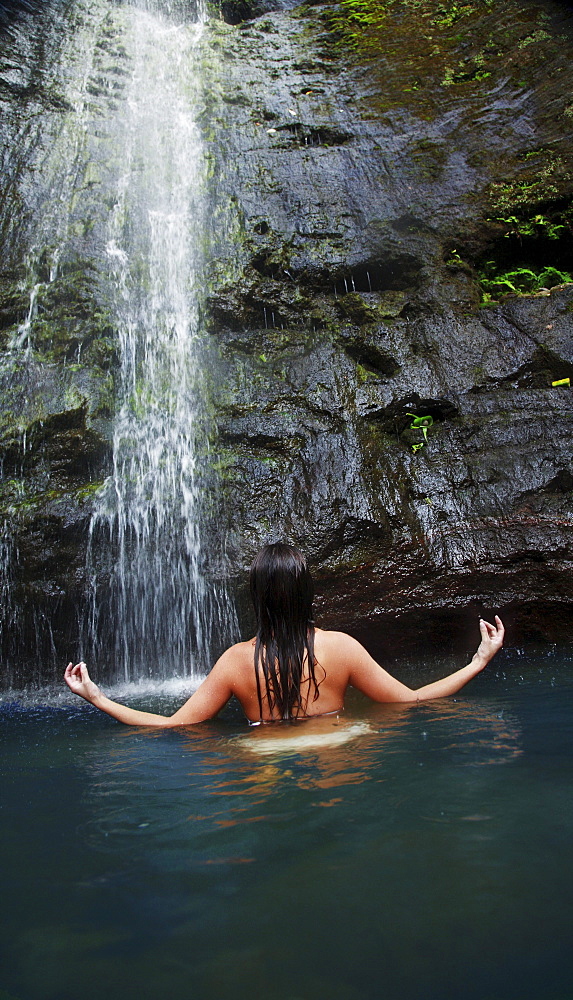 Hawaii, Oahu, Manoa Falls, Beautiful female sitting in a pond at the bottom of Manoa Waterfalls meditating.