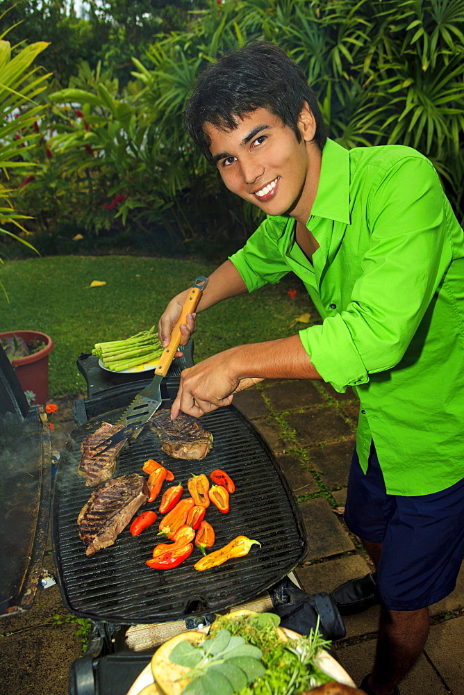 Hawaii, Young man preparing Outdoor barbecue feast in Hawaii garden.