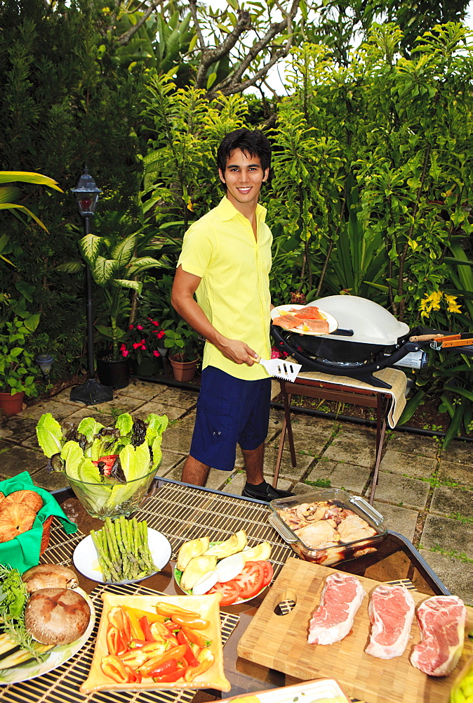 Hawaii, Young man preparing Outdoor barbecue feast in Hawaii garden.