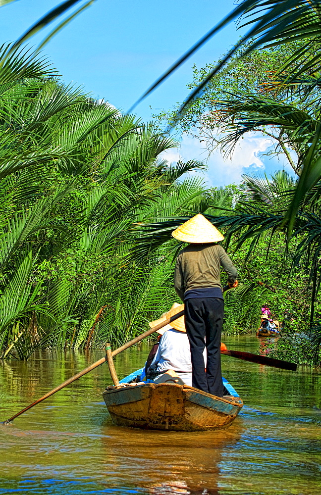 South East Asia, Vietnam, Saigon, Mekong Delta River, Women paddle down a muddy river.