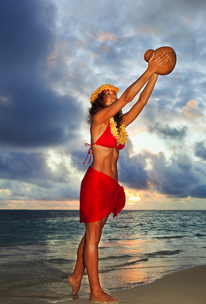 Hawaii, Oahu, Lanikai, Beautiful Hawaiian woman dancing hula on ocean shoreline.