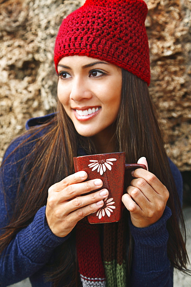 Hawaii, Oahu, Young woman outside in cozy winter weather drinking coffee.