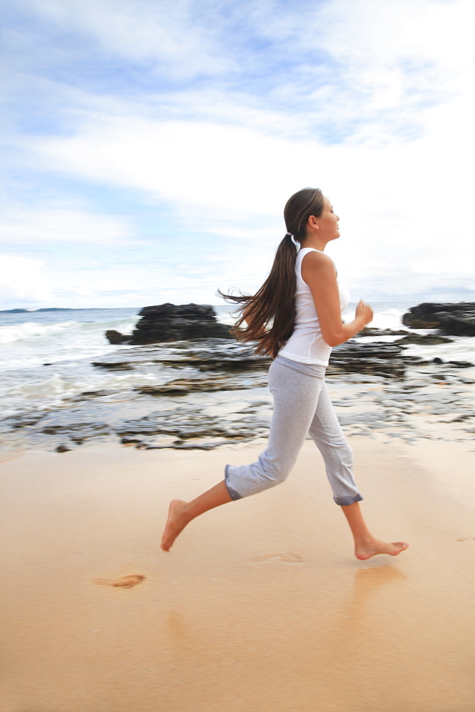 Hawaii, Oahu, Young girl on the beach running in the sand.