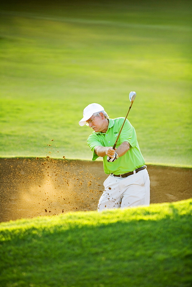 Hawaii, Maui, Male golfer swinging golf club at the Maui Country Club course.