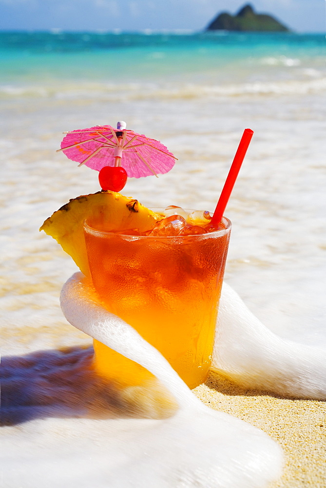 Mai Tai getting splashed by a wave as it rest on the beach.