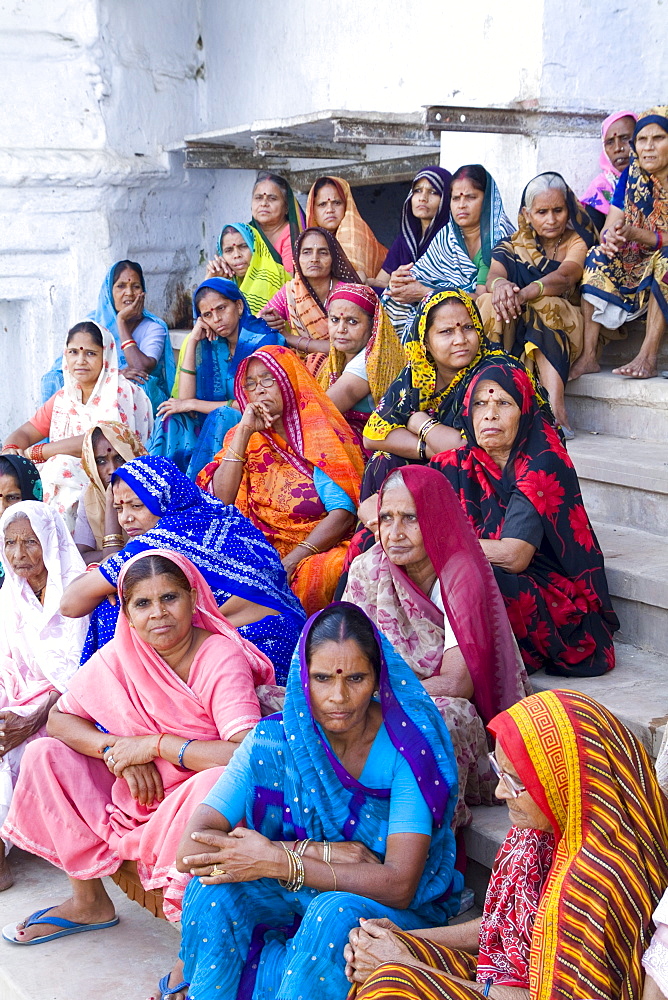 India, Mathura, group of Hindu women in colorful sari and veils sitting on steps.