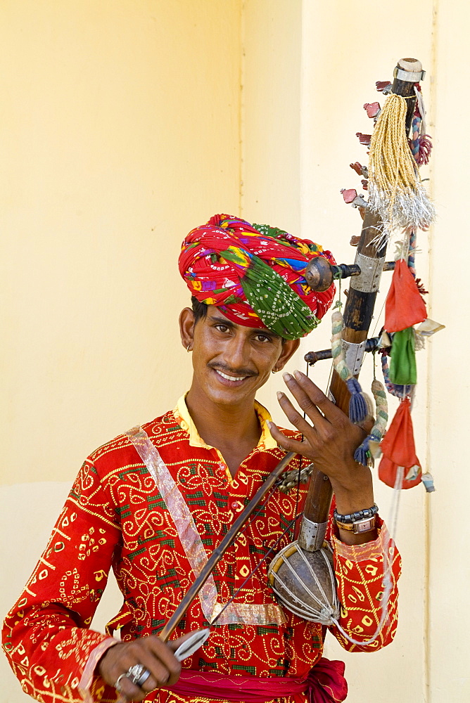 India, Agra, Young man in traditional costume playing instrument called a sarangi.