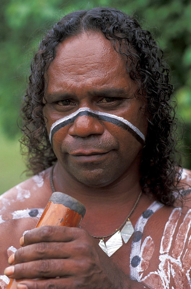 Australia, Queensland, Cairns,  Aboriginal native man holding didgeridoo, paint on body.