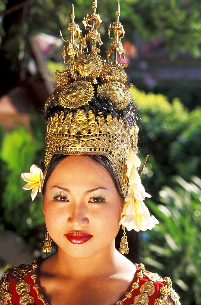 Cambodia, Siem Reap, Portrait of woman in traditional dancing costume, greenery in background.