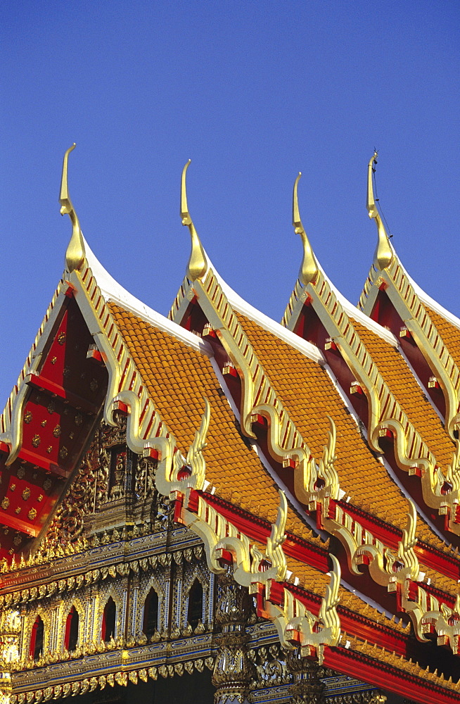 Bangkok, Thailand, Wat Benjamabophit (Marble Temple) top of gold trimmed temple, blue sky.