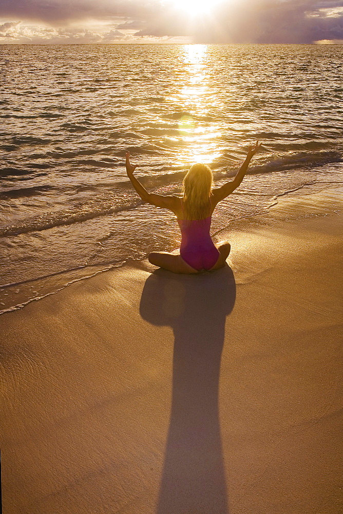 Hawaii, Oahu, Lanikai, woman doing yoga on the beach at sunrise.