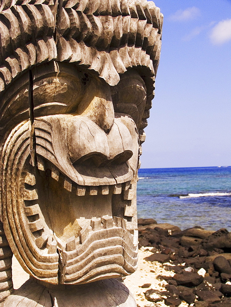 Hawaii, Big Island, Puuhonua O Honaunau, City of Refuge, Close-up of Ki'i in front of blue sky and ocean.