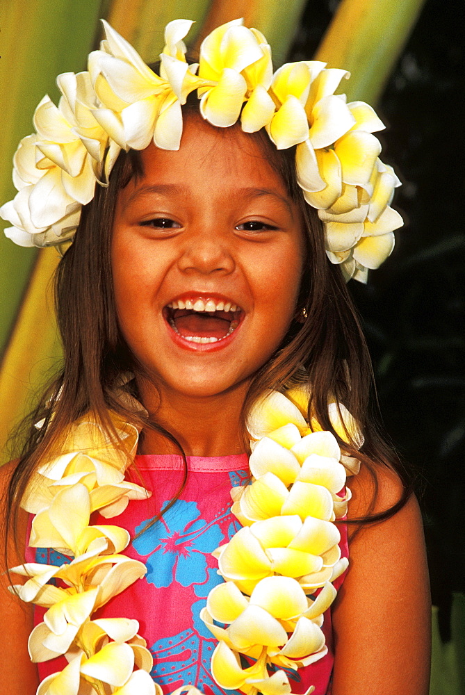 Close-up of young local girl with plumeria leis, greenery background