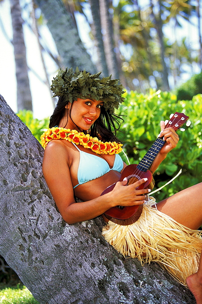 Hawaii, Hula girl with haku and ukulele leaning against tree