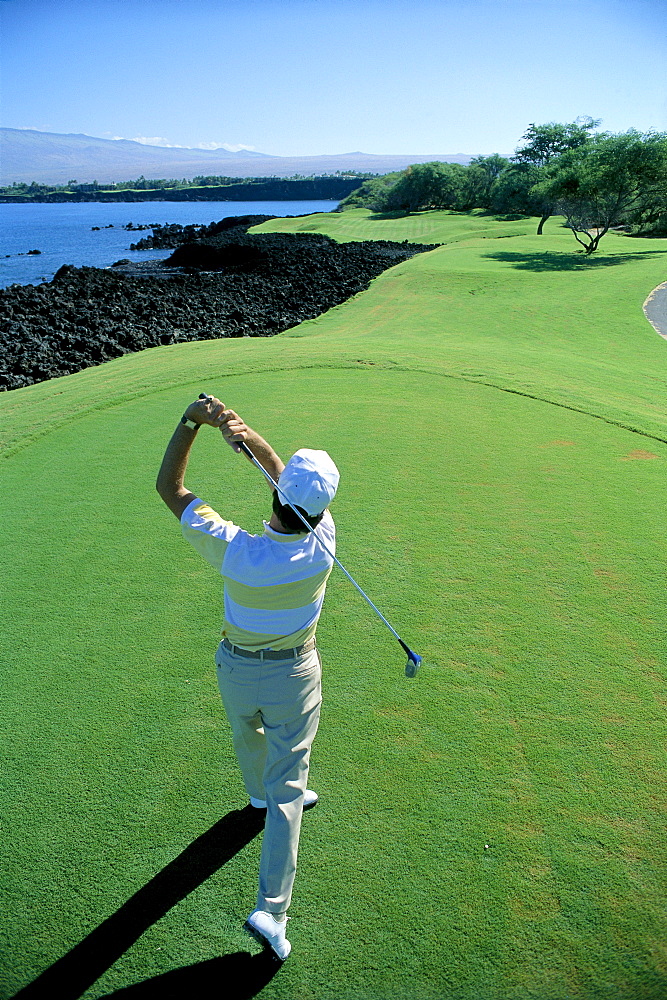 Hawaii, Big Island, Kohala, Mauna Lani Golf Course, 7th Tee, Honokaape tee off, view from behind man swinging A18A. EDITORIAL USE ONLY.