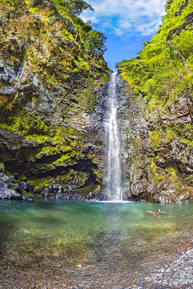 A young lady cools off in a pool below one of the many roadside waterfalls on the road to Hana, Kipahulu, Maui, Hawaii, United States of America