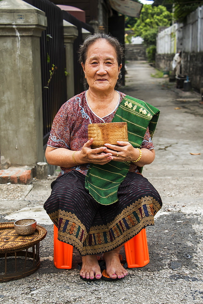 Woman waiting to give Buddhist monks alms on Khounsua Road at dawn, Luang Prabang, Luang Prabang, Laos