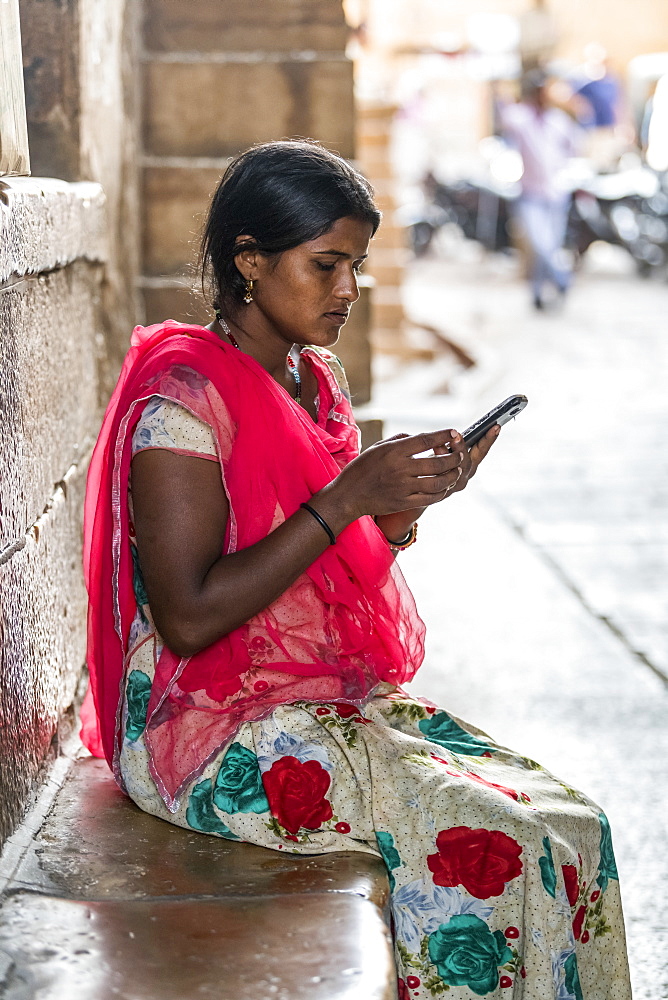 A young Indian woman sits using her cell phone, Jaisalmer, Rajasthan, India