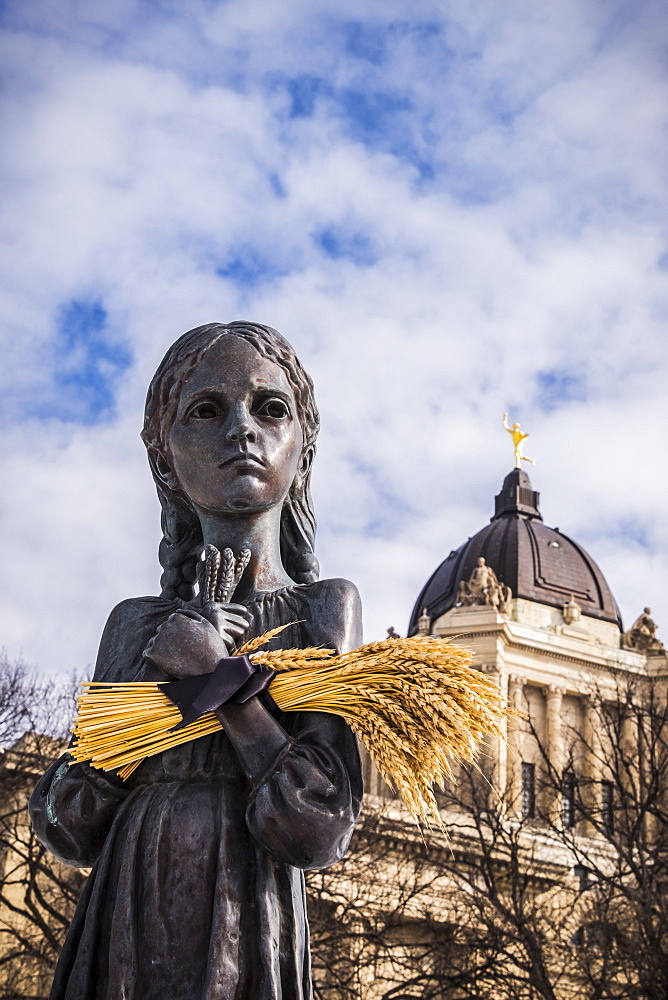 \"Bitter Memories of Childhood” is a memorial statue on the Manitoba Legislative Grounds which pays tribute to the 1932-1933 Ukrainian Famine and Genocide under Soviet ruler Joseph Stalin. The Legislative Building and the Golden Boy are seen in the backgro