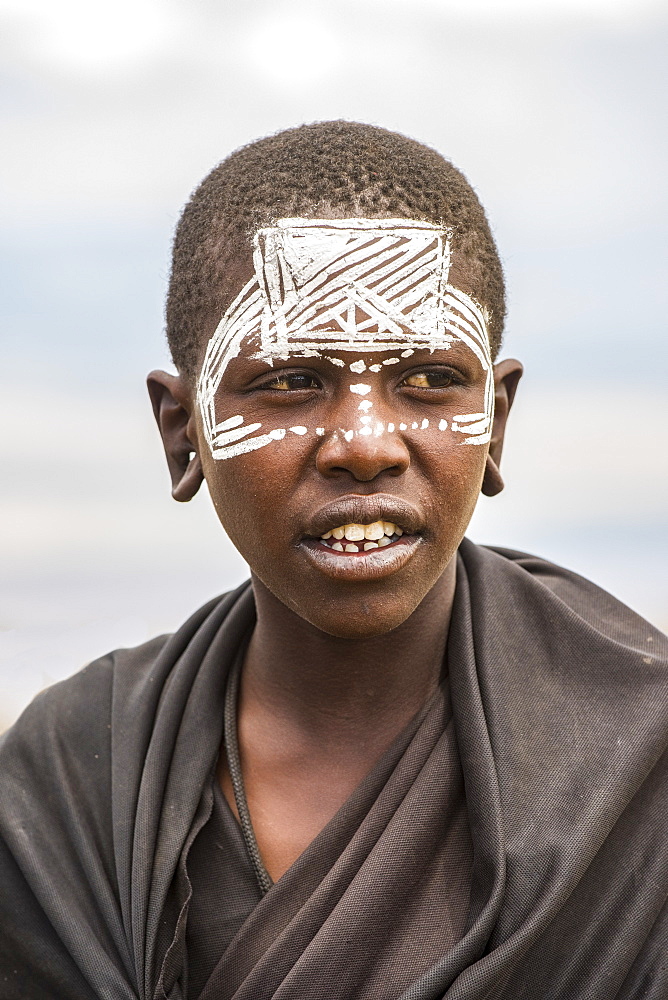 Maasai youth with traditional face paint signifying that he has completed the initiation process for entering adulthood the Ngorongoro Conservation Area, Tanzania