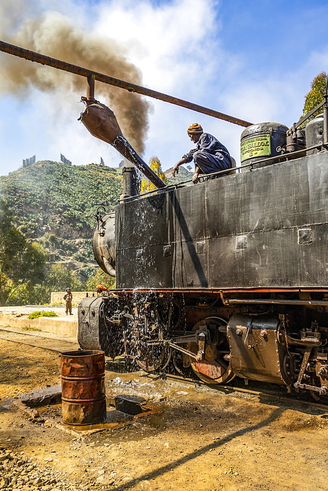 Engineer adding water to the Ansaldo 442 steam locomotive built in 1938, used for transporting cargo from the port city of Massawa to the capital Asmara, Arbaroba, Central Province, Eritrea