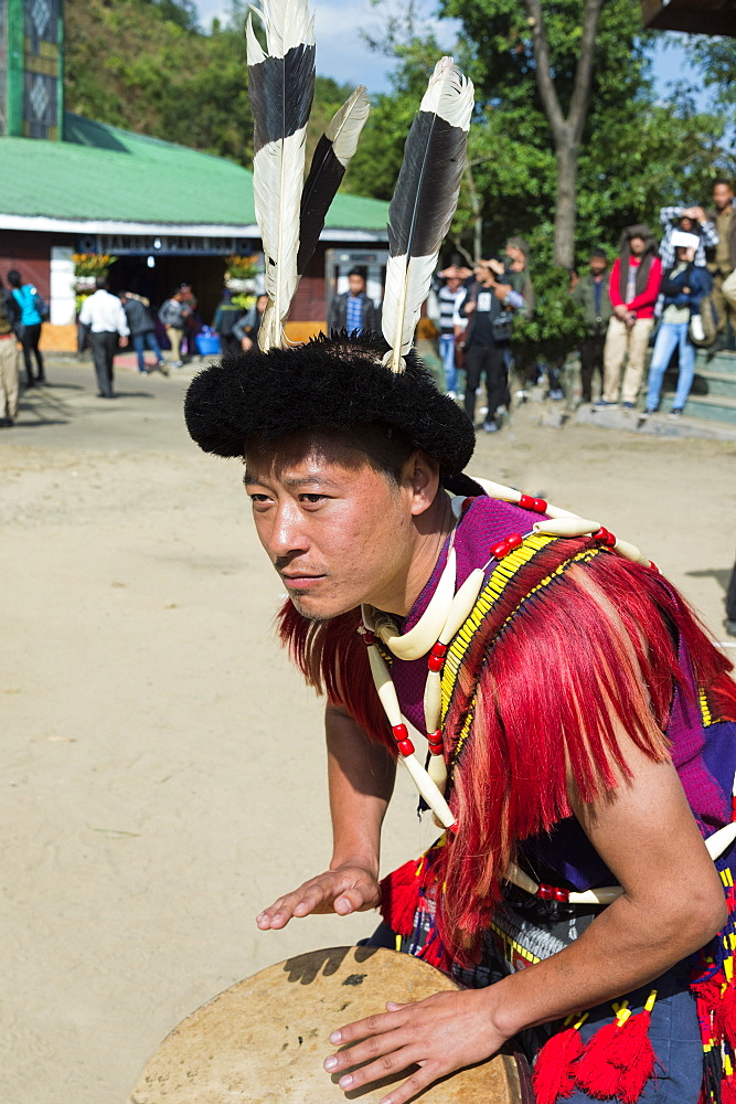 Naga tribal man in traditional outfit playing drum, Kisima Nagaland Hornbill festival, Kohima, Nagaland, India, Asia