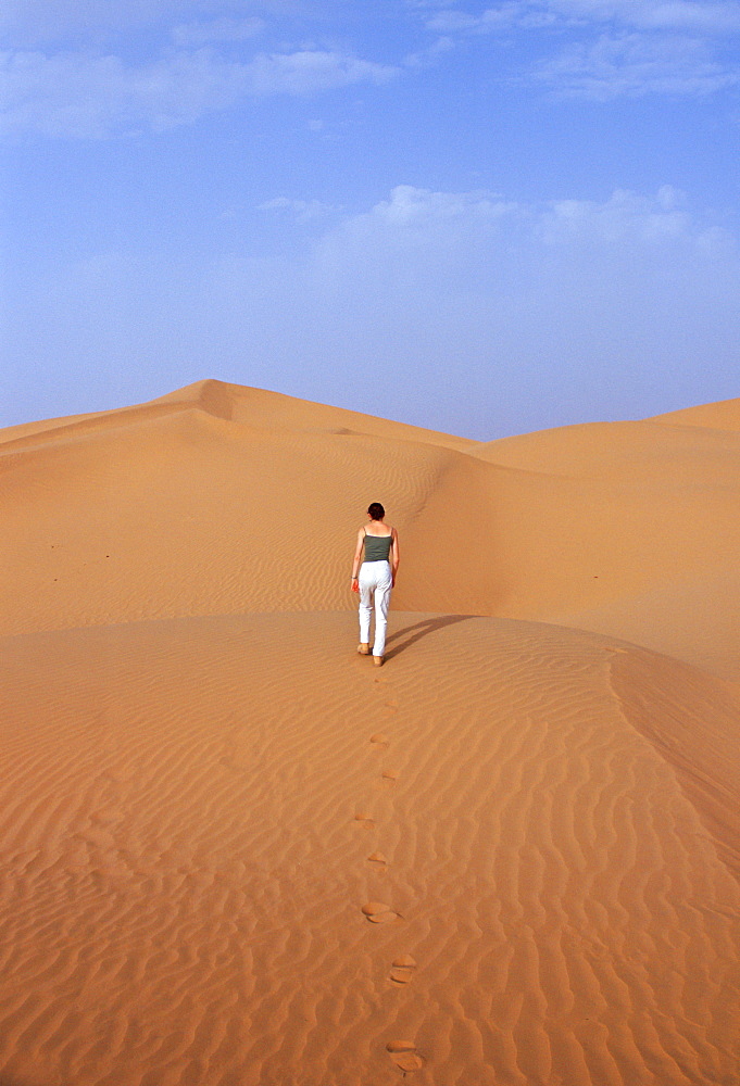 Tourist climbing up a sand dune in the Sahara Desert, Morocco