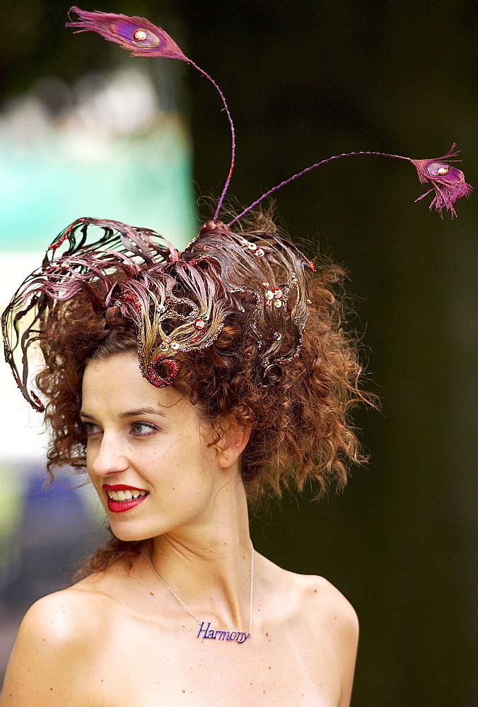 Race-goer wearing a hat which blends in with her hair at Royal Ascot Races. Her necklace has the word 'harmony'