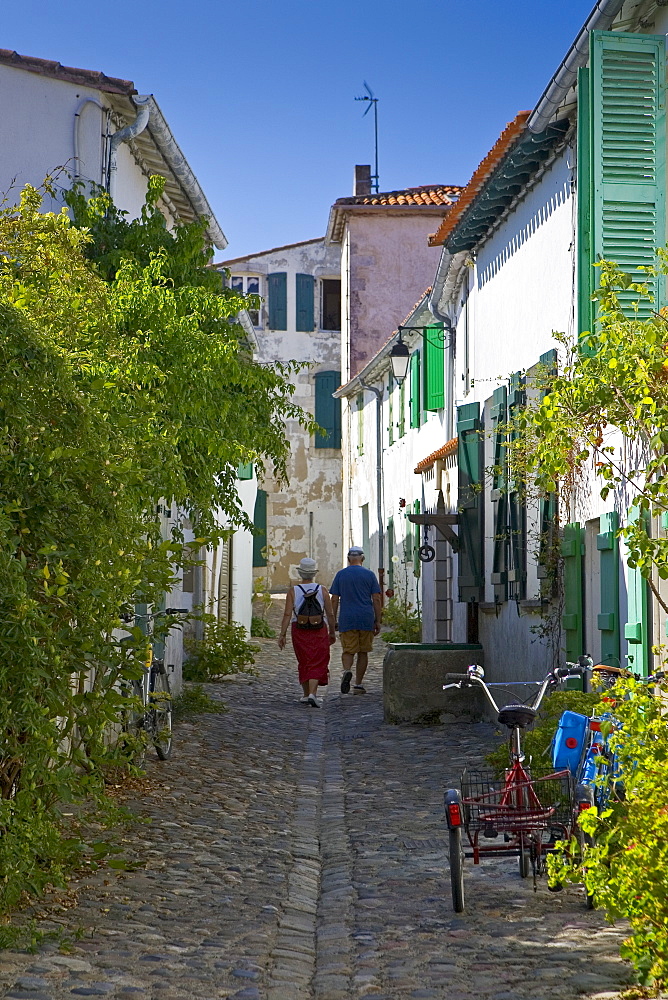 A couple walking down a cobbled street, St Martin, France.