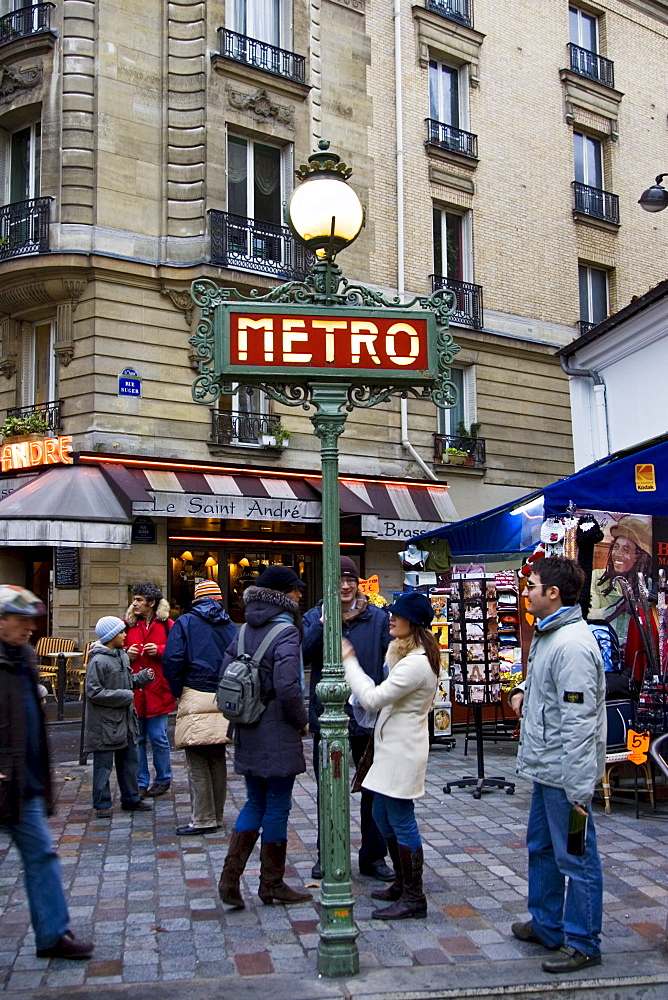 Tourists walk past Metro sign in Boulevard Saint Germain, central Paris, France