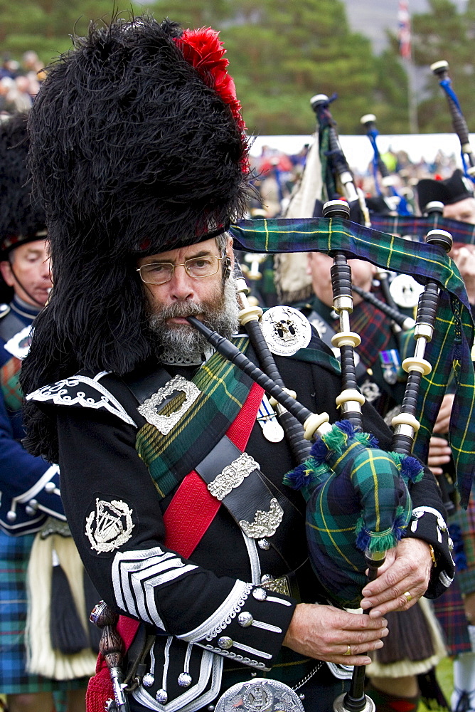 Bagpipe player of massed band of Scottish pipers at Braemar Games Highland Gathering, Scotland