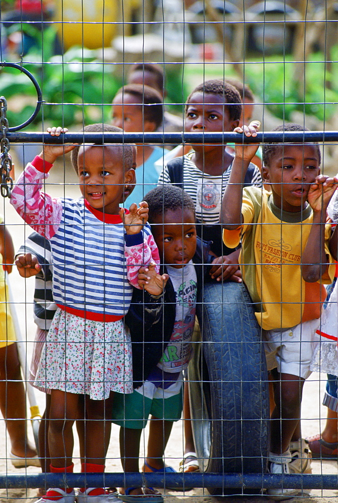 South African Children peering through a fence